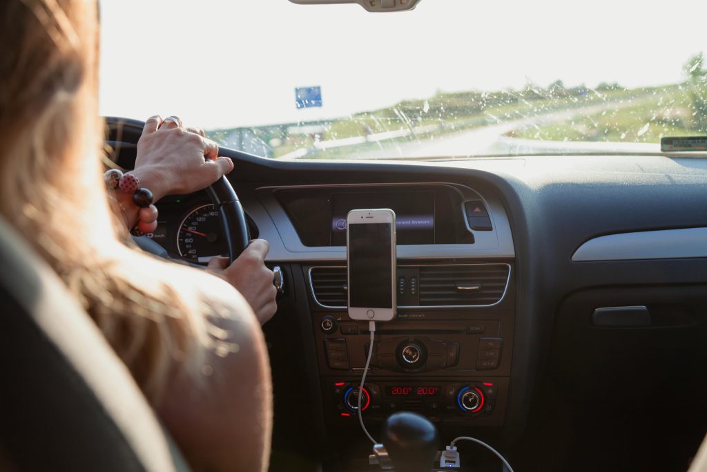 A woman drives a car on the highway. The point-of-view is from the backseat of the car.