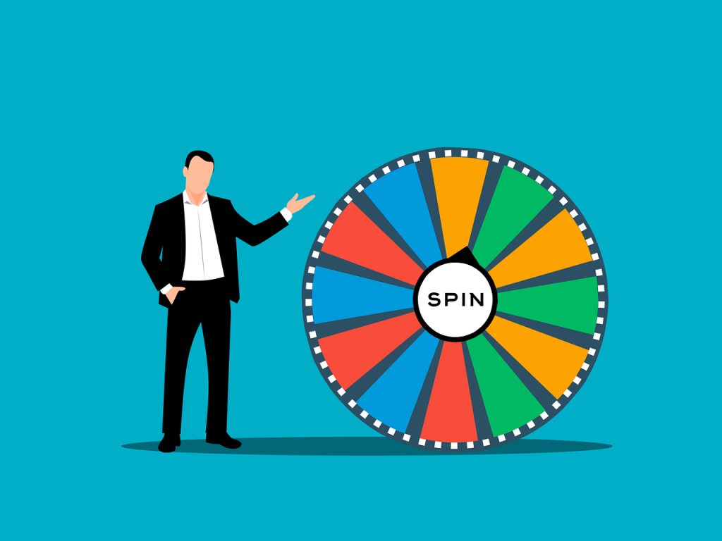 A man in a suit stands beside a prize wheel